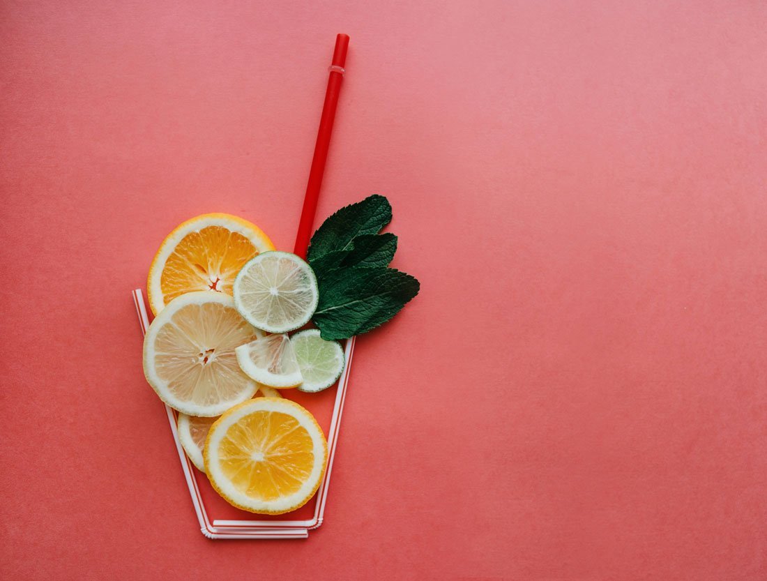 An artistic expression of infused-water that features slices of fruit within a cup made of straws.